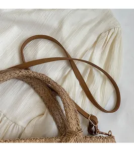 Detail of woven tote bag featuring a brown leather adjustable shoulder strap and gold hardware
