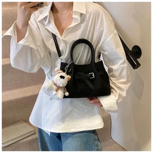 Détail d'un sac bandoulière noir avec charmant petit chien en peluche sur un escalier