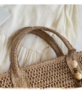 Close-up of woven straw tote bag featuring wide handles and decorative wooden beads