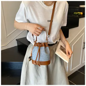 Détail d'un sac seau en denim bleu avec cuir marron et fermeture à cordon coulissant