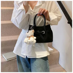 Détail du sac seau en daim noir avec boucle argentée et breloque agneau blanc