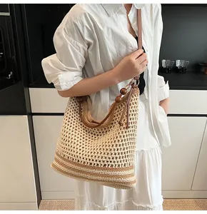 Dettaglio della borsa tote tessuta a righe beige, cinturini in pelle e perline di legno