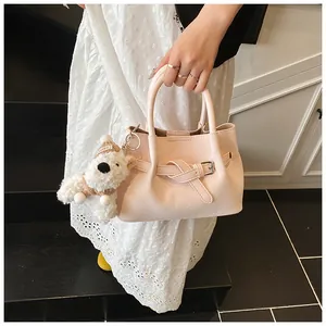 Détail du sac panier tressé rose avec boucle en cuir et accessoire en peluche de chiot blanc