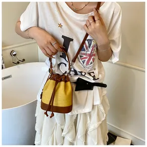 Détail du sac seau contrasté avec tissu jaune et bandoulière en cuir marron sur modèle
