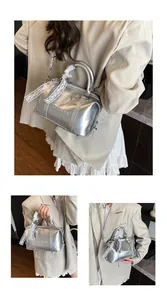 Detail view of silver Boston bag with metallic finish, double handles, and lace ribbon bow