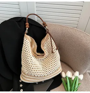 Dettaglio borsa tote intrecciata boho con perle di legno e manici in pelle marrone