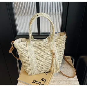 Detail of woven tote bag featuring beige hollow texture, tassel beads and leather strap