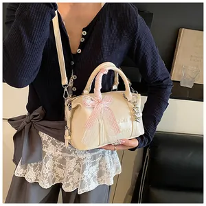Detail of creamy white pillow bag featuring pink lace ribbon handles and heart pendant