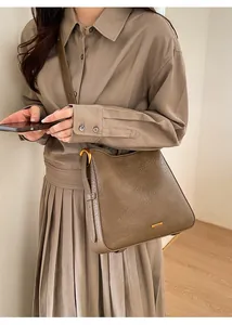Detail of vintage khaki tote bag showing pebble leather texture and gold logo plaque