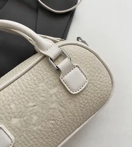 Close-up of cream bowling bag showing soft lychee grain leather and silver metal buckles