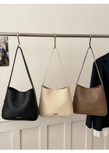 Detailed view of three vintage tote bags in black, beige, and brown with gold logo plate