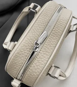 Close-up of smooth metal zipper and lychee pattern leather on beige bowling bag