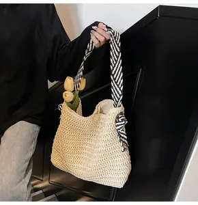 Detalle del bolso tote de paja tejida con asa de cinta a rayas blancas y negras