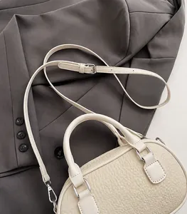 Detail of cream bowling bag with lychee texture and silver hardware on a blazer
