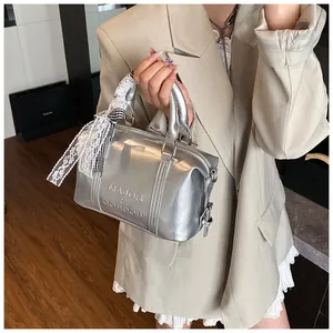 Close-up of silver metallic Boston bag with logo embossing and decorative lace scarf