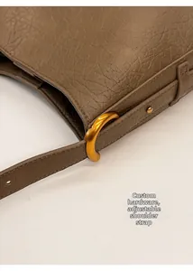 Detail of textured leather tote featuring custom C-shaped hardware and adjustable strap
