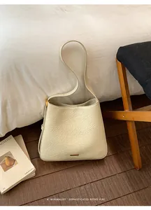 Close-up of cream textured leather tote bag with gold metal hardware in a minimalist room
