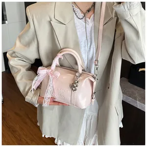 Close-up of pink patent leather Boston bag with lace bow and heart-shaped charms