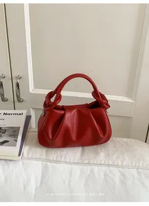 Detail der roten Plissee-Handtasche mit Lederstruktur und rundem Metallgriffring