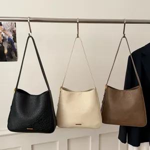 Three minimalist tote bags in black, beige, and brown with gold logo and pebble texture