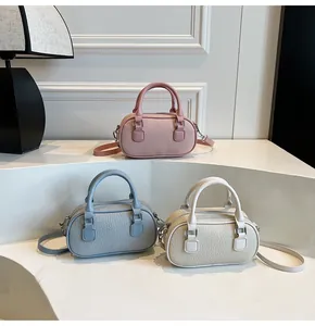 Three mini Boston bags in pink, blue, and white with litchi grain texture on display