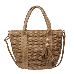 Large hand-woven straw tote bag with brown leather strap and wooden bead tassel