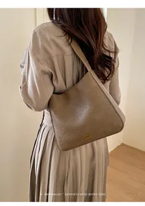 Detailed macro view of brown vintage textured leather tote bag with a gold brand plaque