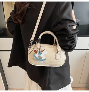 Close-up of cream bowling bag with lychee grain leather and cute horse charm