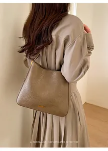 Close-up of a vintage mud-brown tote bag with pleated leather texture and metal logo detail