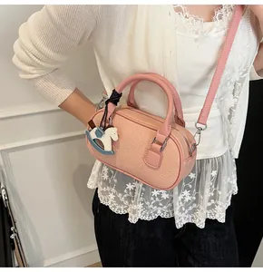Detail of pink pebbled leather bowling bag with blue rocking horse charm on white top