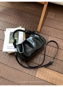 Detail der schwarzen Cloud Bag mit Faltenoptik und verstellbarem Gurt auf Holz