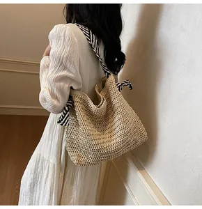 Detalle de bolso tote de paja tejido a mano con asa de cinta de seda a rayas blancas y negras