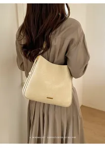 Close-up of minimalist apricot tote bag featuring natural pleated texture and gold logo plate