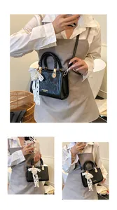Detail van zwarte crossbody tas met geplooide textuur en parel hart hanger