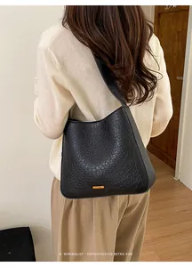Detail of black pebbled leather texture on a retro hobo bag worn on the shoulder