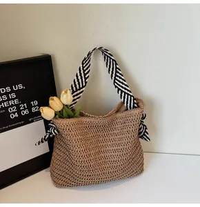 Detalle del bolso de paja natural con correas a rayas y decoración de tulipanes