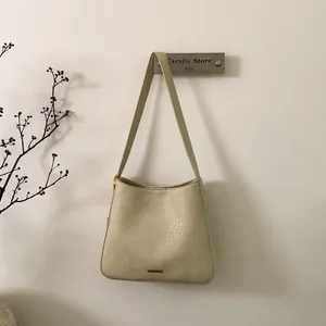 Detail of cream leather tote bag featuring vintage wrinkled texture and metal logo