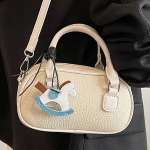 Chic off-white pebble leather bowling bag with a cute horse charm and crossbody strap
