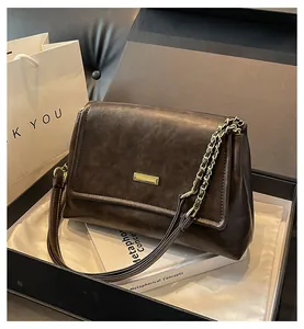 Detail view of dark brown leather tote bag with gold chain strap in premium gift box