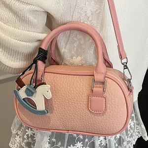 Pink lychee texture mini bowling bag with cute horse charm shown as a crossbody bag