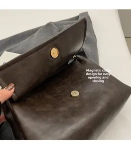 Detail view of the magnetic gold closure on dark brown faux leather shoulder bag
