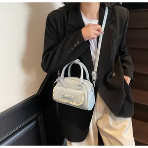 Close-up of light blue lace bowling bag with ribbon handle on a stylish blazer outfit