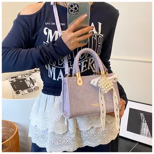 Detail van lavendel crossbody tas met geweven handvaten en parel kant hanger accessoire