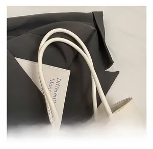 Detail show of white woven tote bag with silver buckle and plush sheep charm
