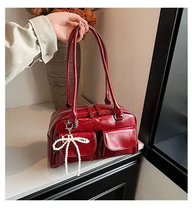 Close-up of deep red patent leather Boston bag with beaded bow and front flap pockets