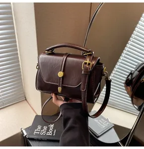 Detail of vintage dark brown faux leather handbag with retro gold buckle and top handle