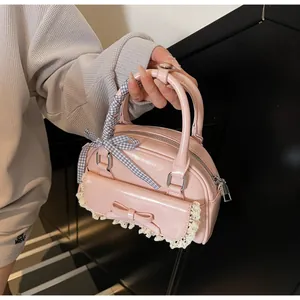 Close-up of pink patent leather handbag featuring lace trim and ribbon handle bow