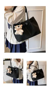 Detail of black woven leather tote bag with a cute white plush puppy charm pendant