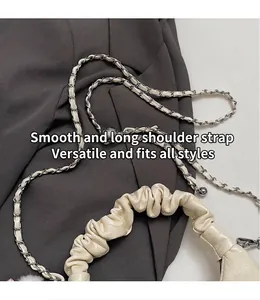 Detail van scrunchie handvat en gevlochten kettingriem op een crème crossbodytas