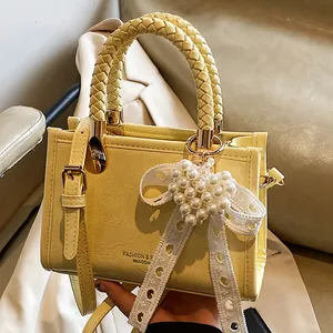 Chique lichtgele crossbodytas met geweven handvat en elegant parelmoer strikaccessoire